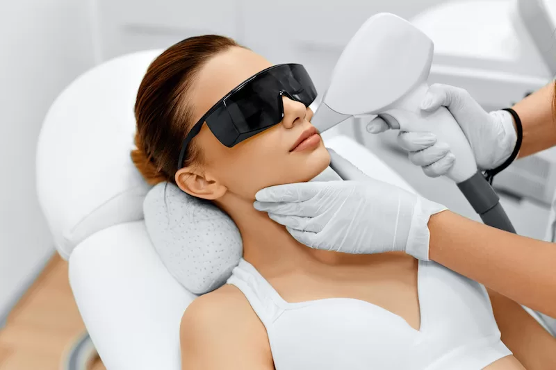 The beautician giving laser epilation treatment to young woman's face and body at beauty clinic to achieve hairless smooth and soft skin.